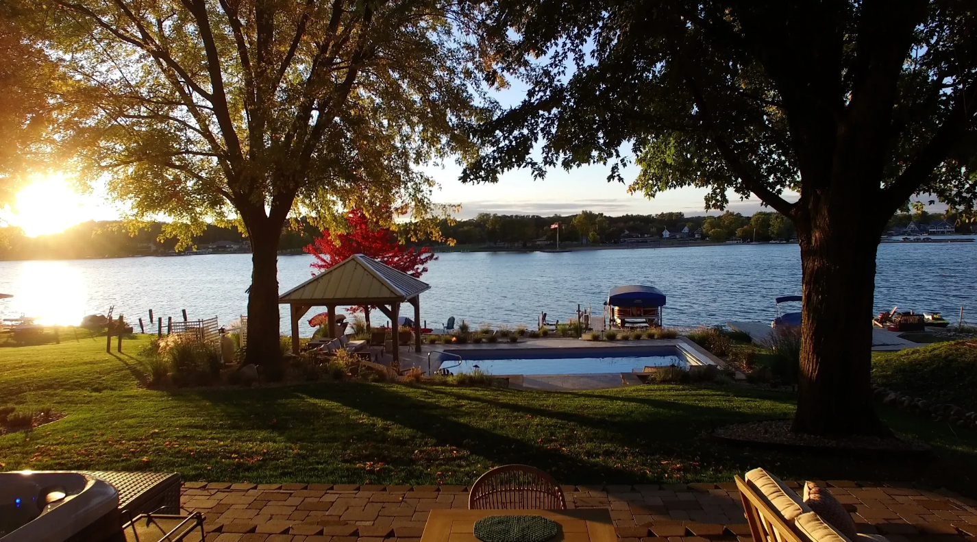 the sun is setting over a lake with a gazebo in the background