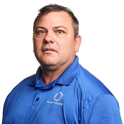 A middle-aged man with short, dark hair wearing a blue polo shirt with a logo, looking directly at the viewer.