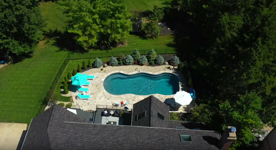 An aerial view showcasing a house with a pool and breathtaking landscape in the backyard.