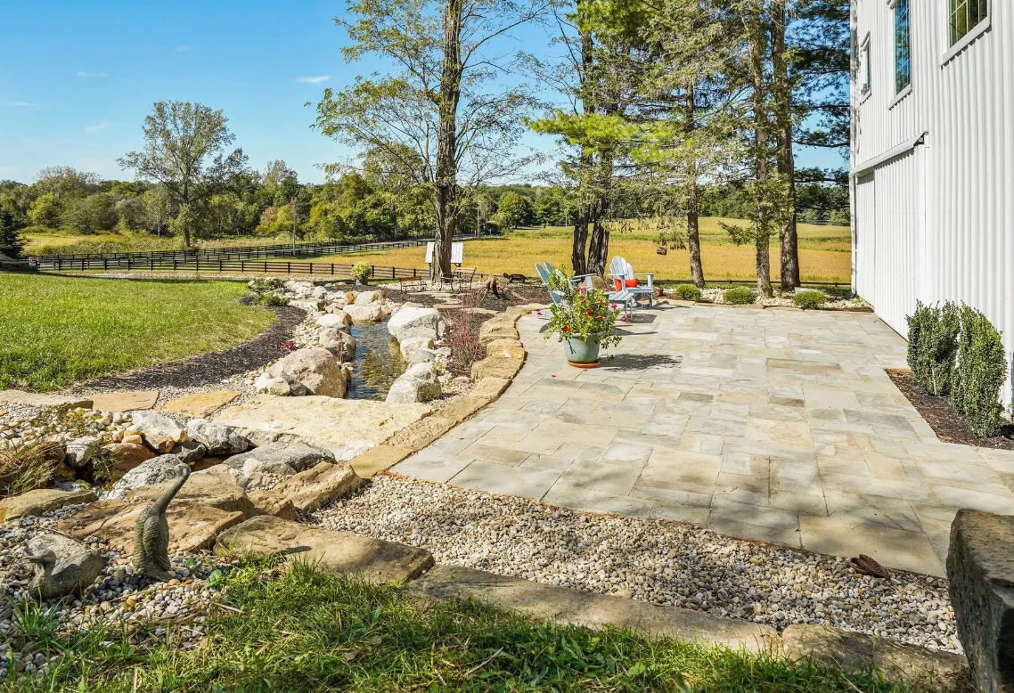 A serene backyard with a stone patio and a tranquil water feature, creating a peaceful outdoor oasis.