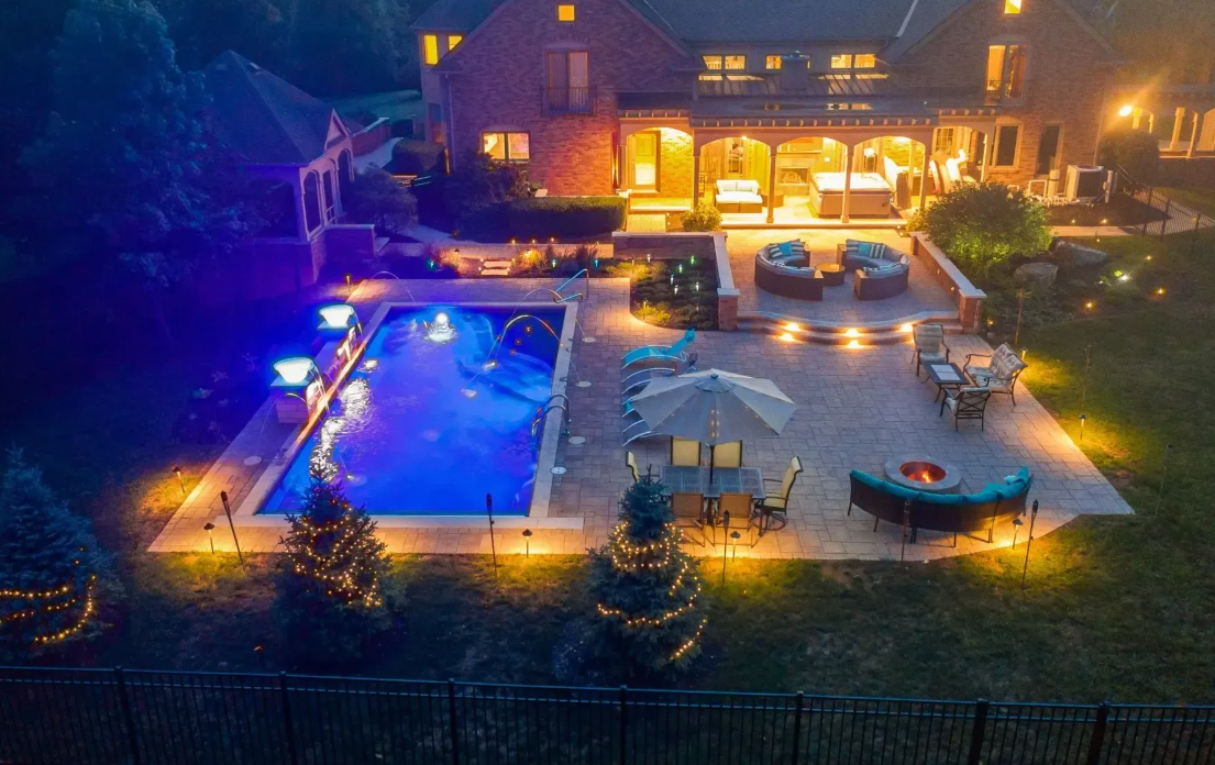 A well-lit backyard pool with patio lighting, creating a serene and inviting atmosphere.