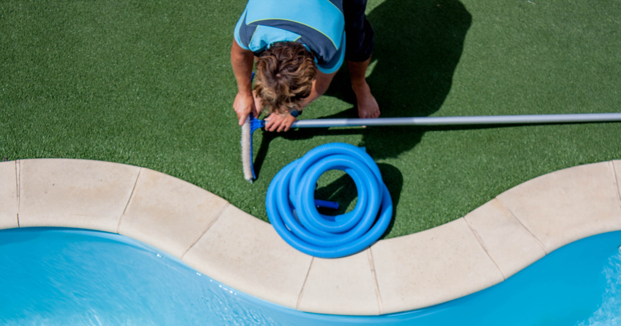 A pool  guy cleaning a pool with a hose and pool brush