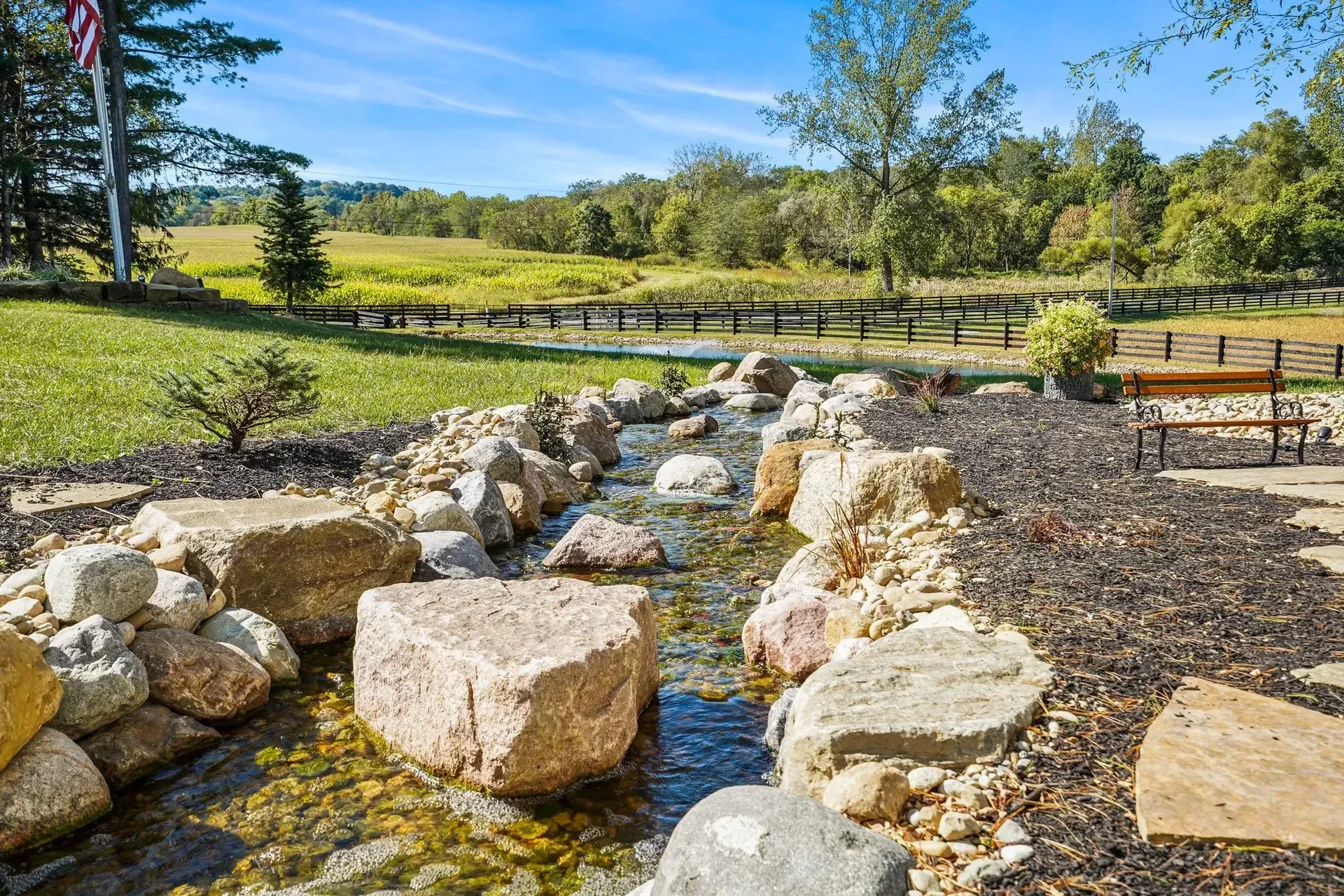 A small stream surrounded by rocks and trees in a park.