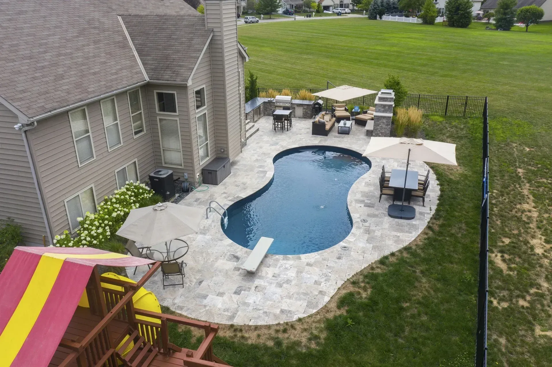 An aerial view of a backyard with a large swimming pool and patio furniture.