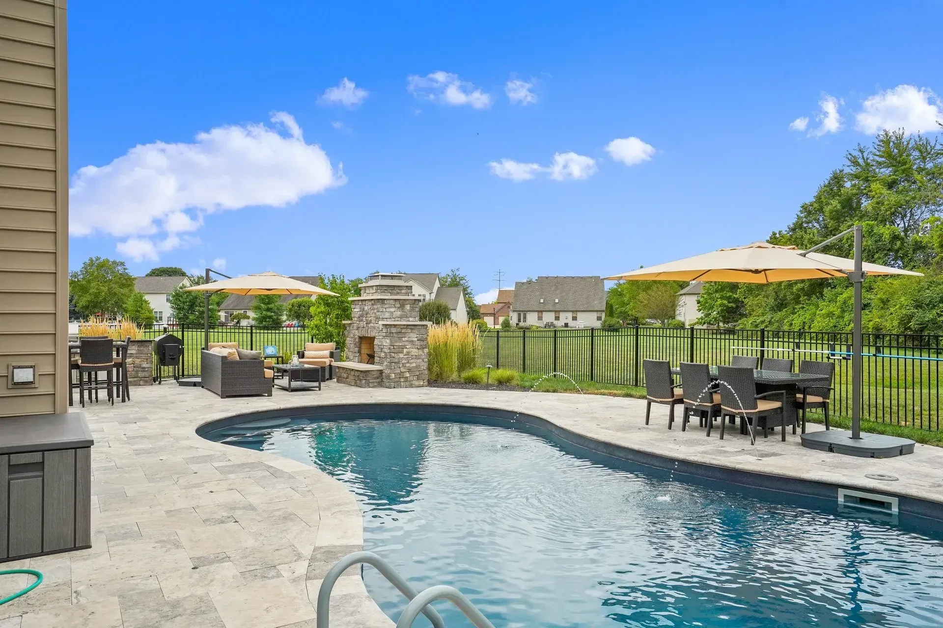 A large swimming pool surrounded by patio furniture and umbrellas.
