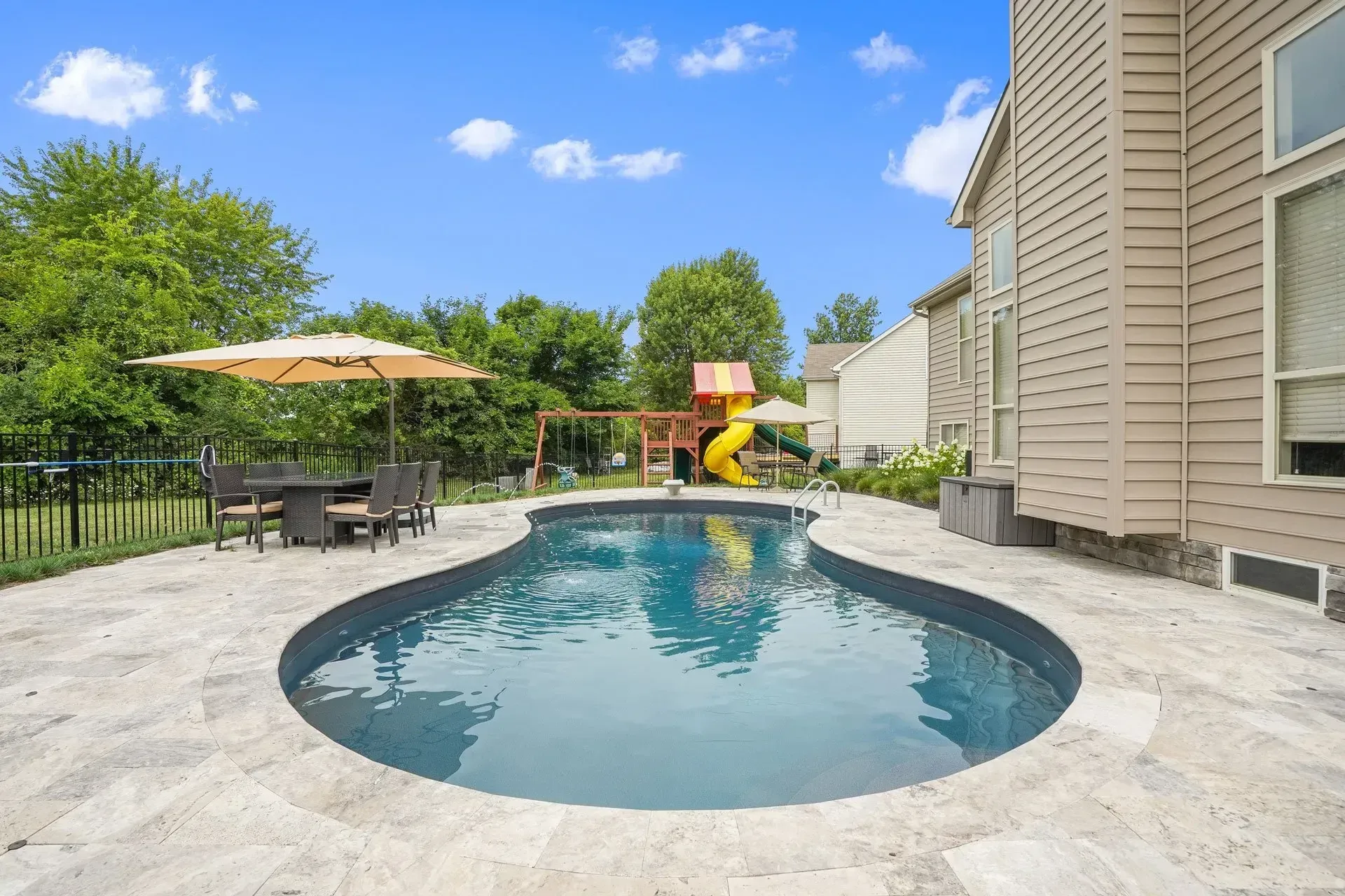 There is a large swimming pool in the backyard of a house.
