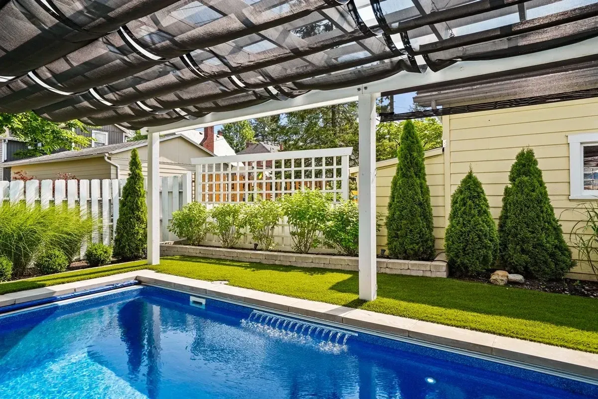 There is a large swimming pool in the backyard of a house.
