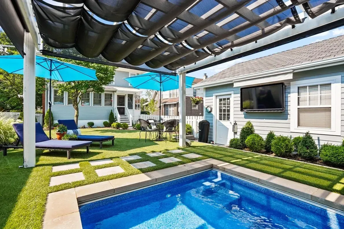 There is a large swimming pool in the backyard of a house.