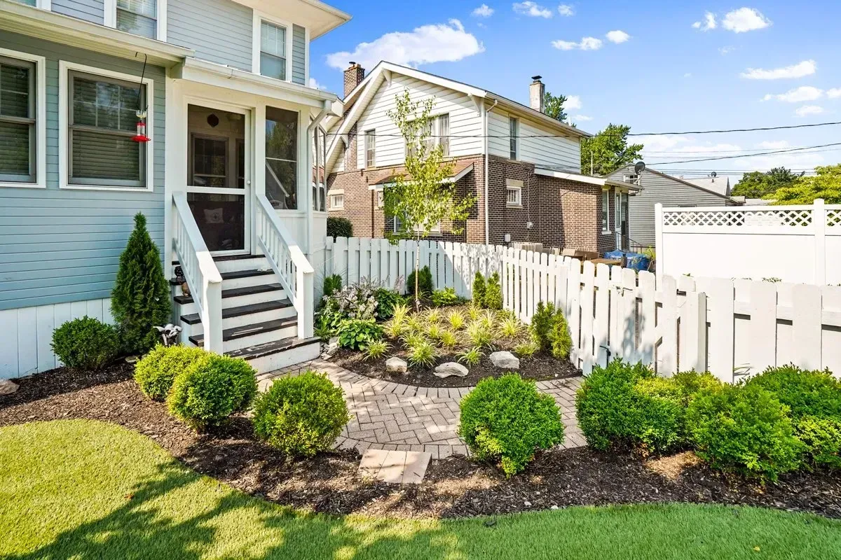 A house with a white picket fence and a lush green yard.