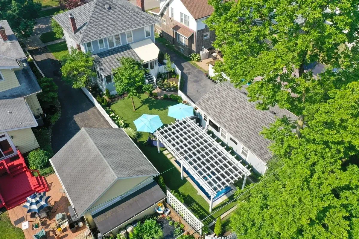 An aerial view of a house with a pergola in the backyard