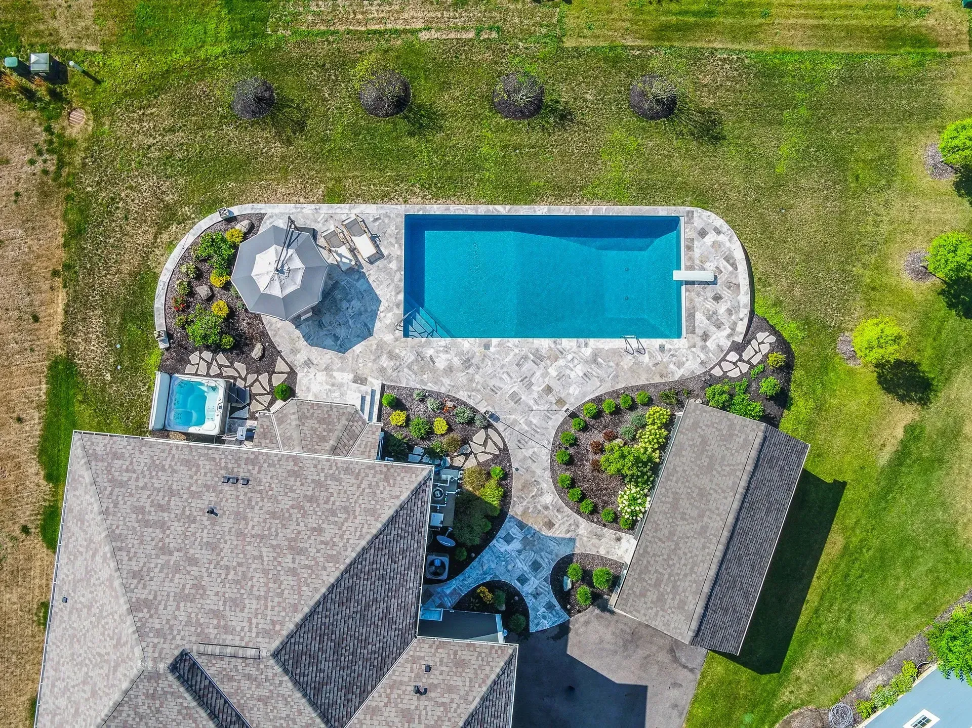 An aerial view of a house with a large swimming pool in the backyard.