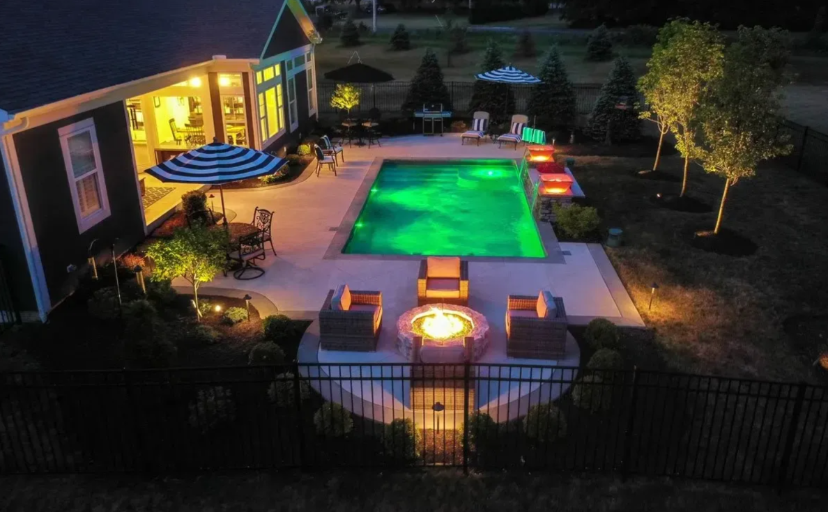 Backyard featuring a pool and fire pit, enhanced by pool lighting for a cozy ambiance.