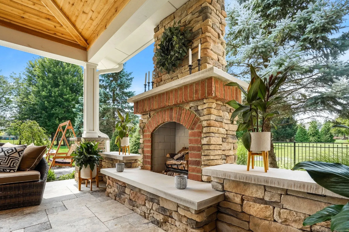 An outdoor patio with a stone fireplace and patio furniture.
