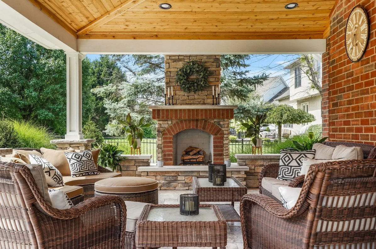 An outdoor patio with wicker furniture and an outdoor fireplace.