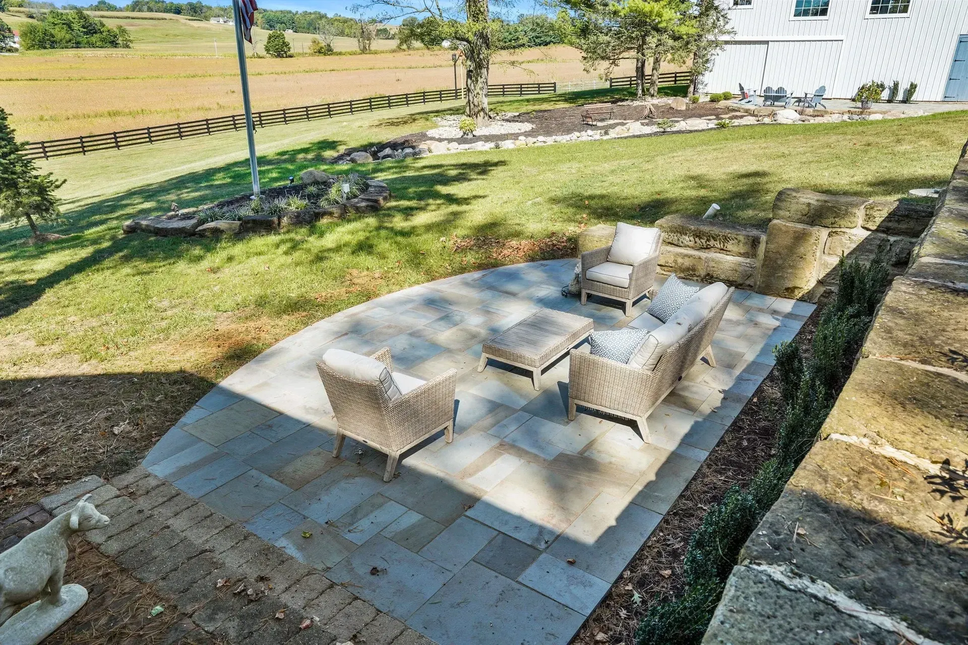 A patio with chairs and a table in the backyard of a house.