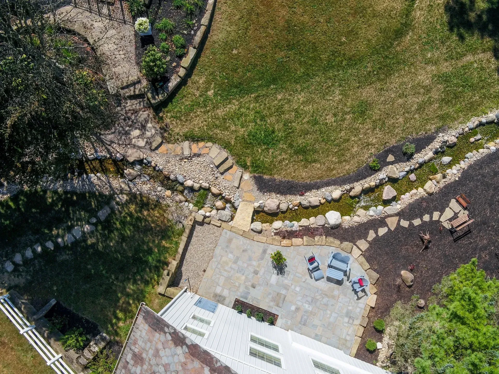 An aerial view of a backyard with a patio and a waterfall.