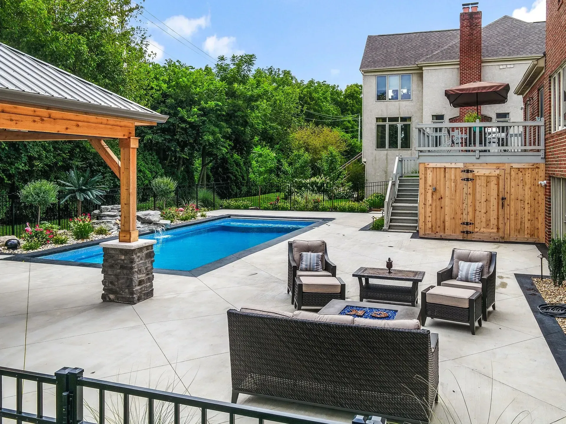 Backyard with pool, patio furniture, and a gazebo. A multi-story house is in the background.