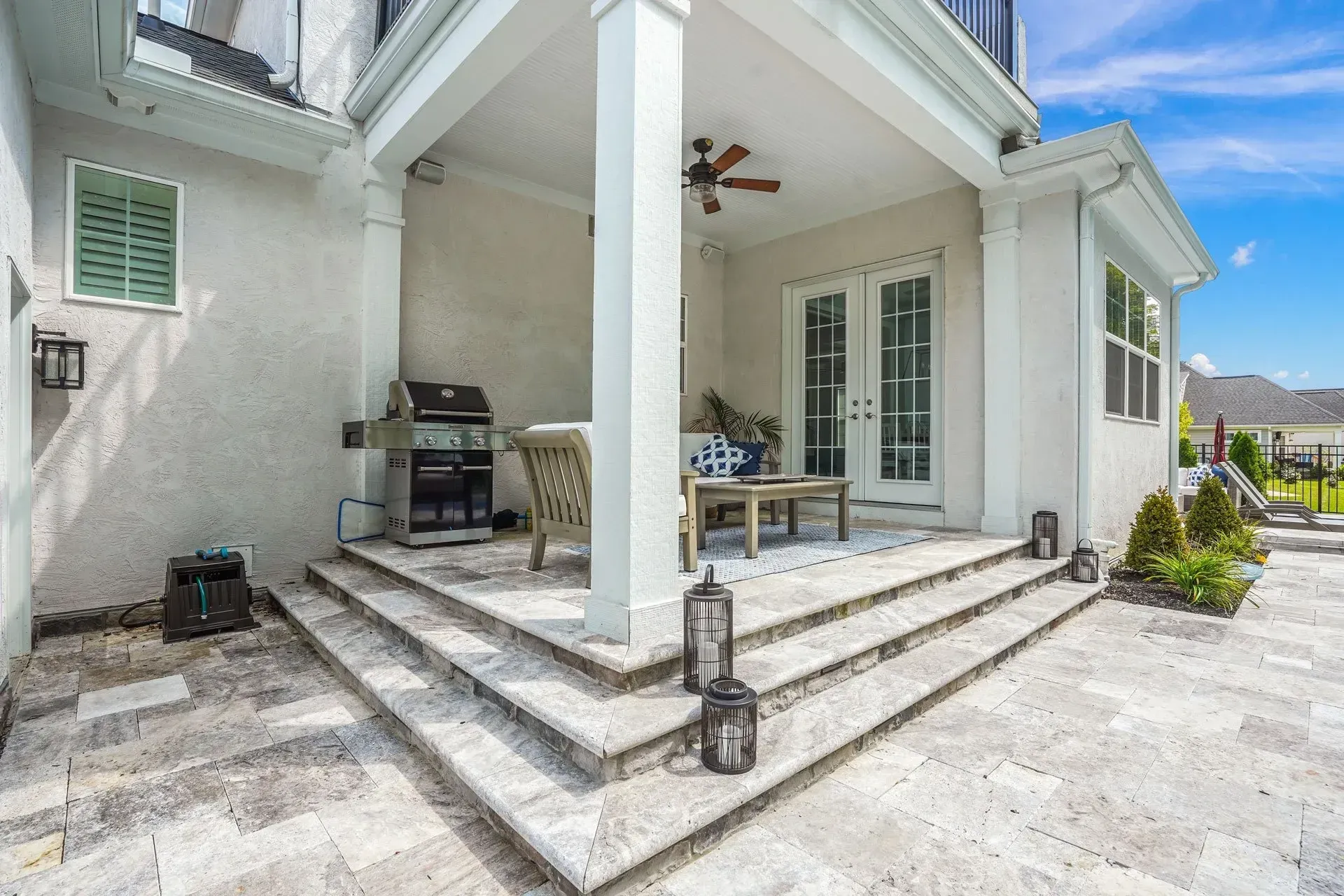 There is a patio with a grill and chairs on it.