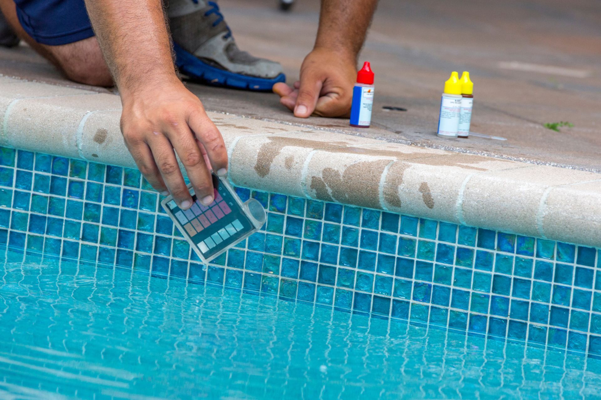 Pool maintenance worker checking the quality of water  using pool test kit