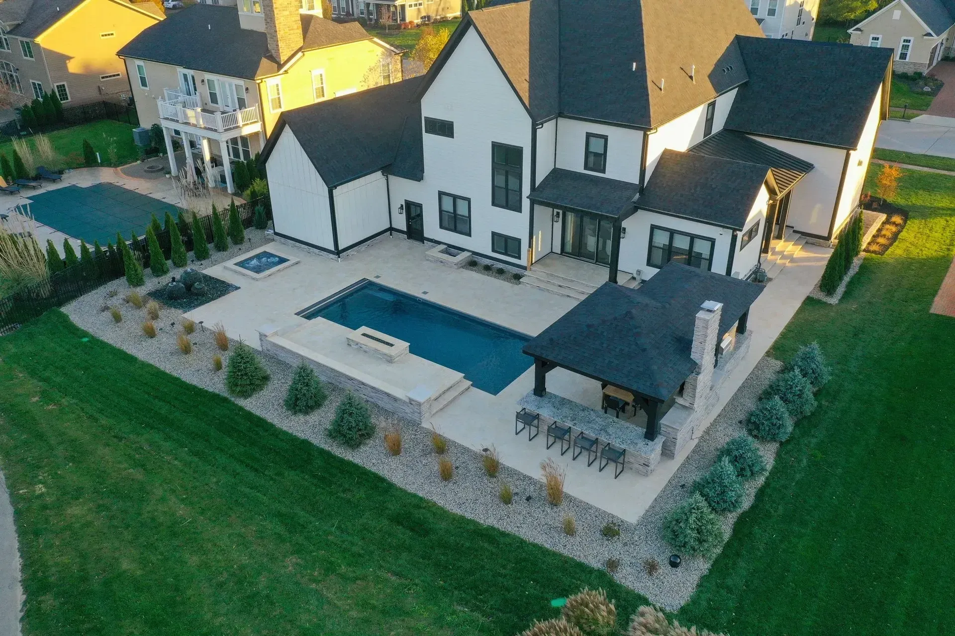 An aerial view of a large house with a large swimming pool in the backyard.