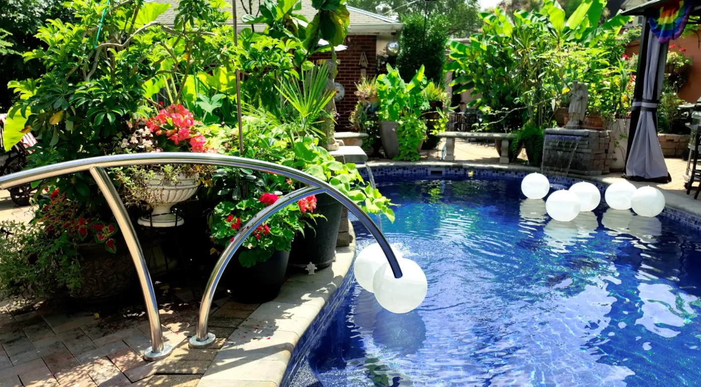 A pool surrounded a garden with a waterfall  and white garden balls