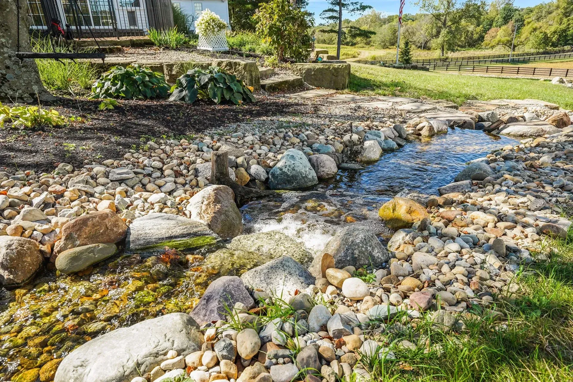 A stream running through a rocky area in a yard.