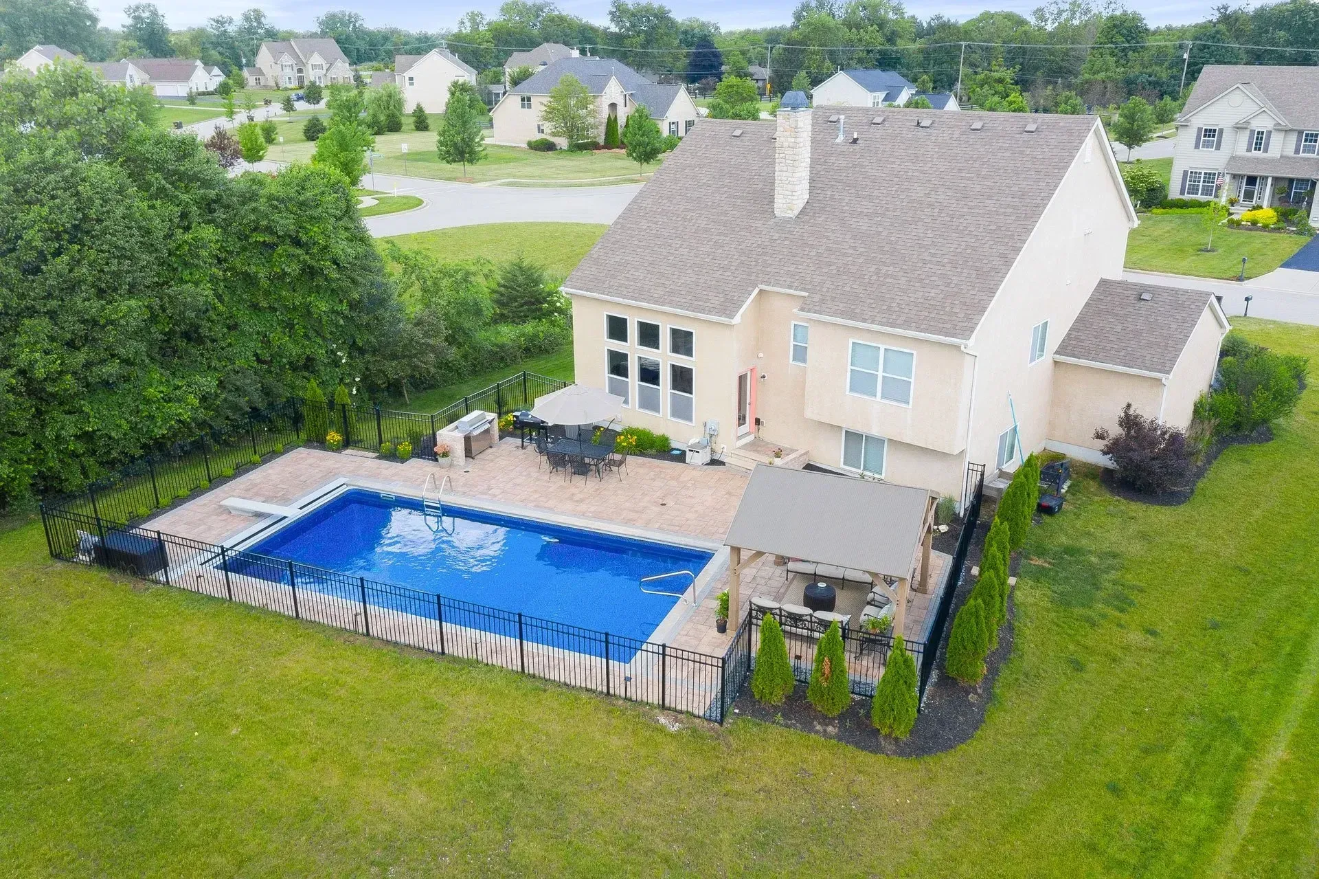 A large house with a backyard swimming pool. The pool has a surrounding deck and a gazebo area.