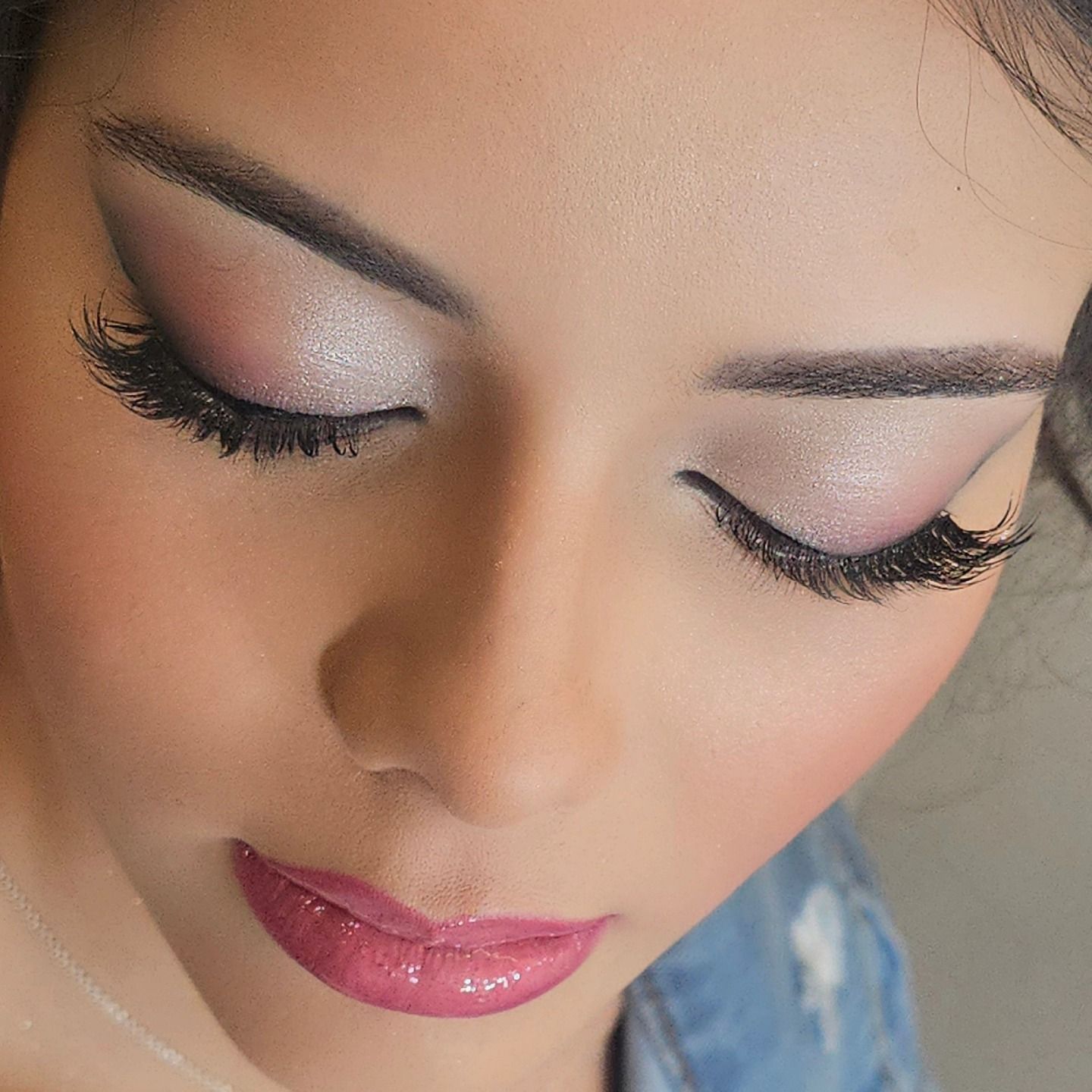 Donna con trucco occhi rosa e argento, ciglia scure e labbra rosa lucide.