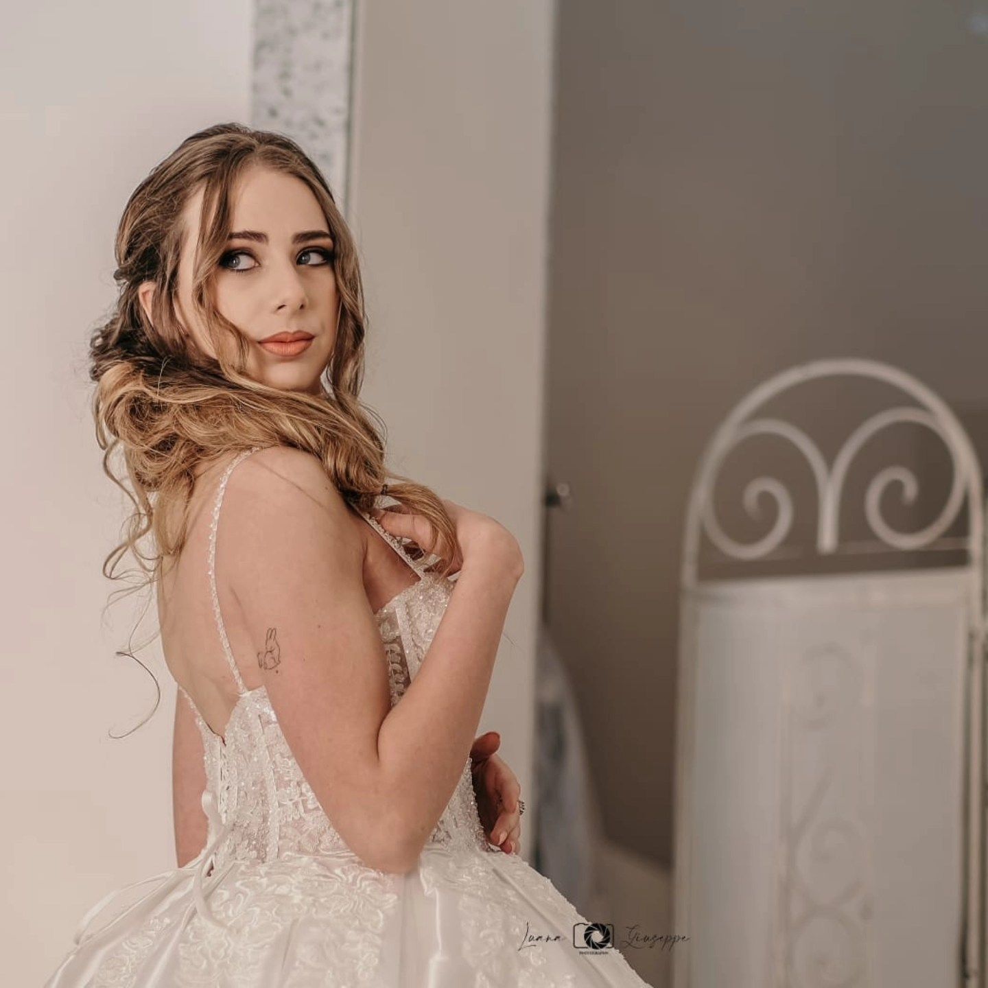 Una donna in abito da sposa bianco guarda oltre la sua spalla.