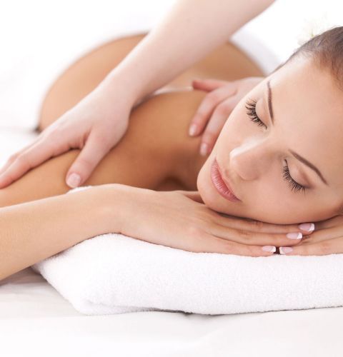 Donna che riceve un massaggio alla schiena, sdraiata a faccia in giù, con gli occhi chiusi su un asciugamano bianco.