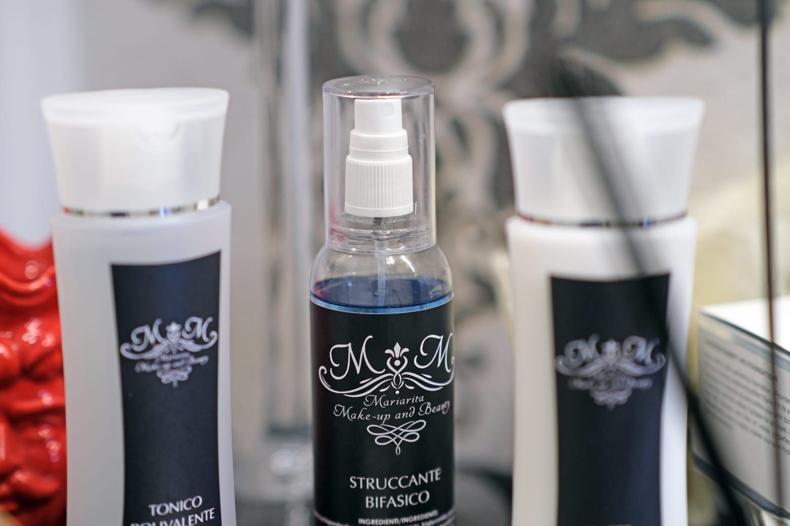 Tre bottiglie bianche con etichette nere, liquido blu in un flacone spray.