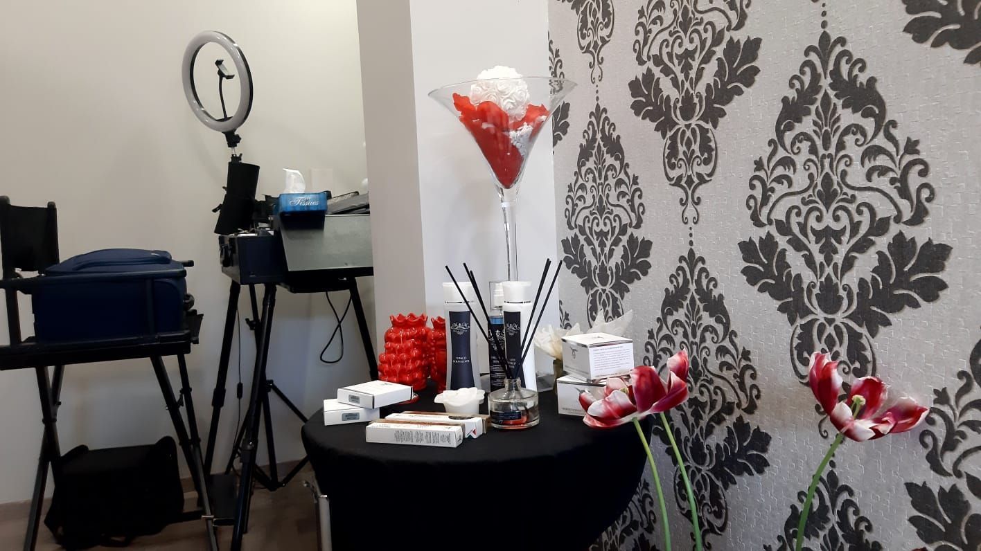 Una postazione trucco con prodotti esposti su un tavolo contro una parete decorata, con tulipani in primo piano.