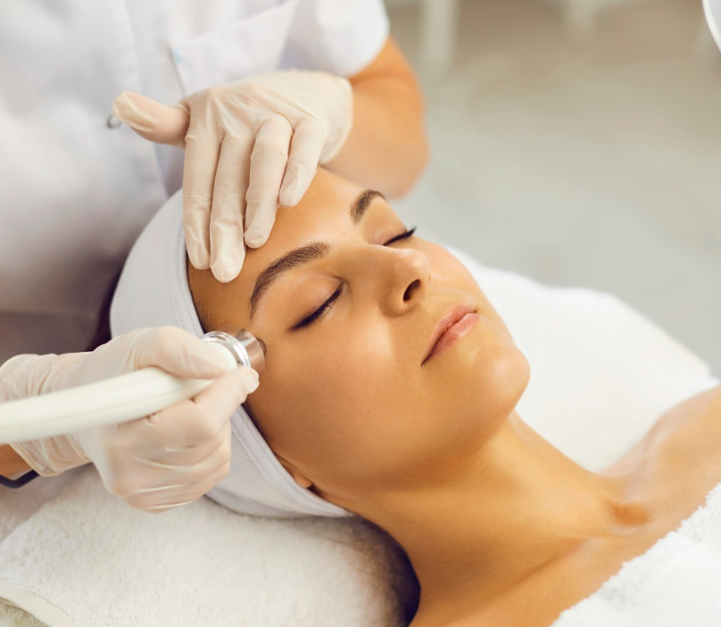 Donna che riceve un trattamento viso in una spa, mentre un tecnico le applica un dispositivo sul viso.