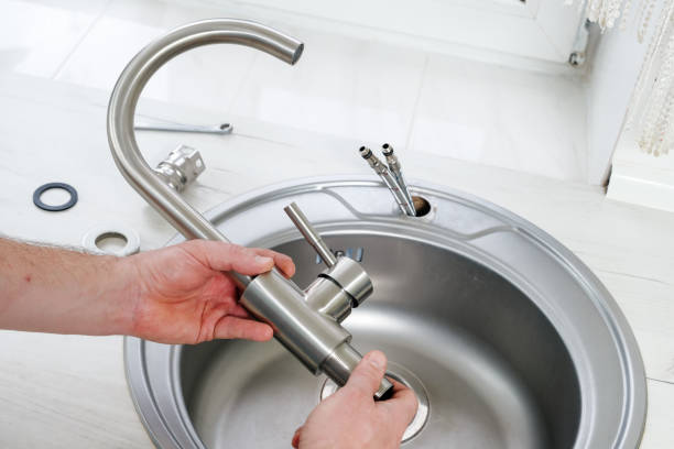 A person is fixing a faucet in a kitchen sink.