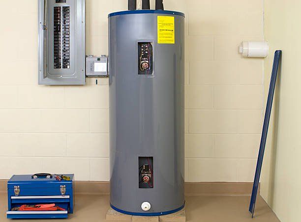 A water heater is sitting in a room next to a toolbox.