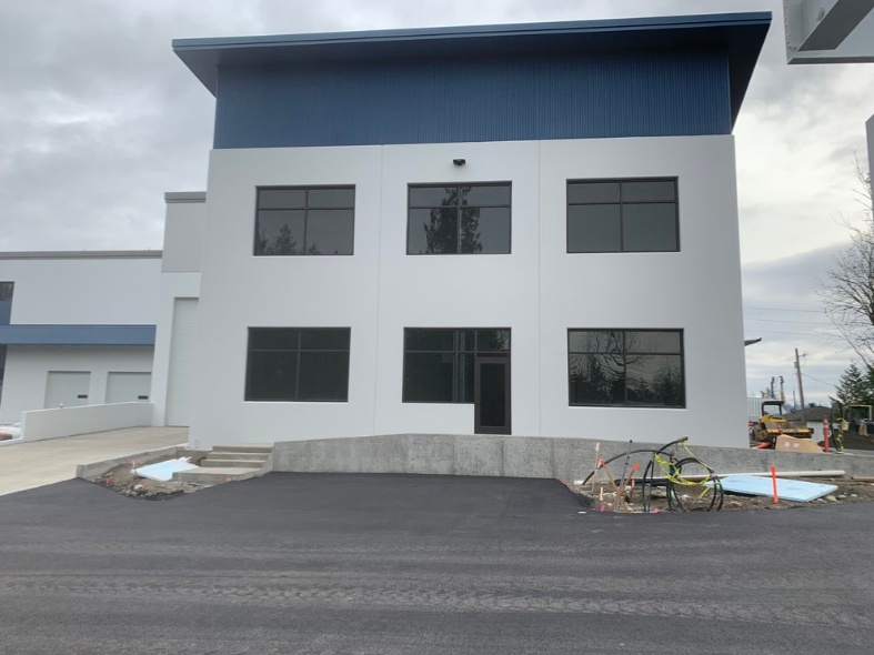 A large white building with black windows and a blue roof