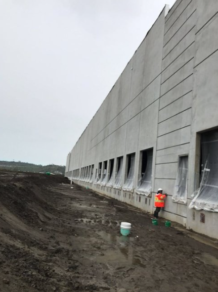 A man in an orange vest is standing in front of a large building