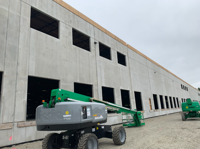 A construction vehicle is parked in front of a building under construction.
