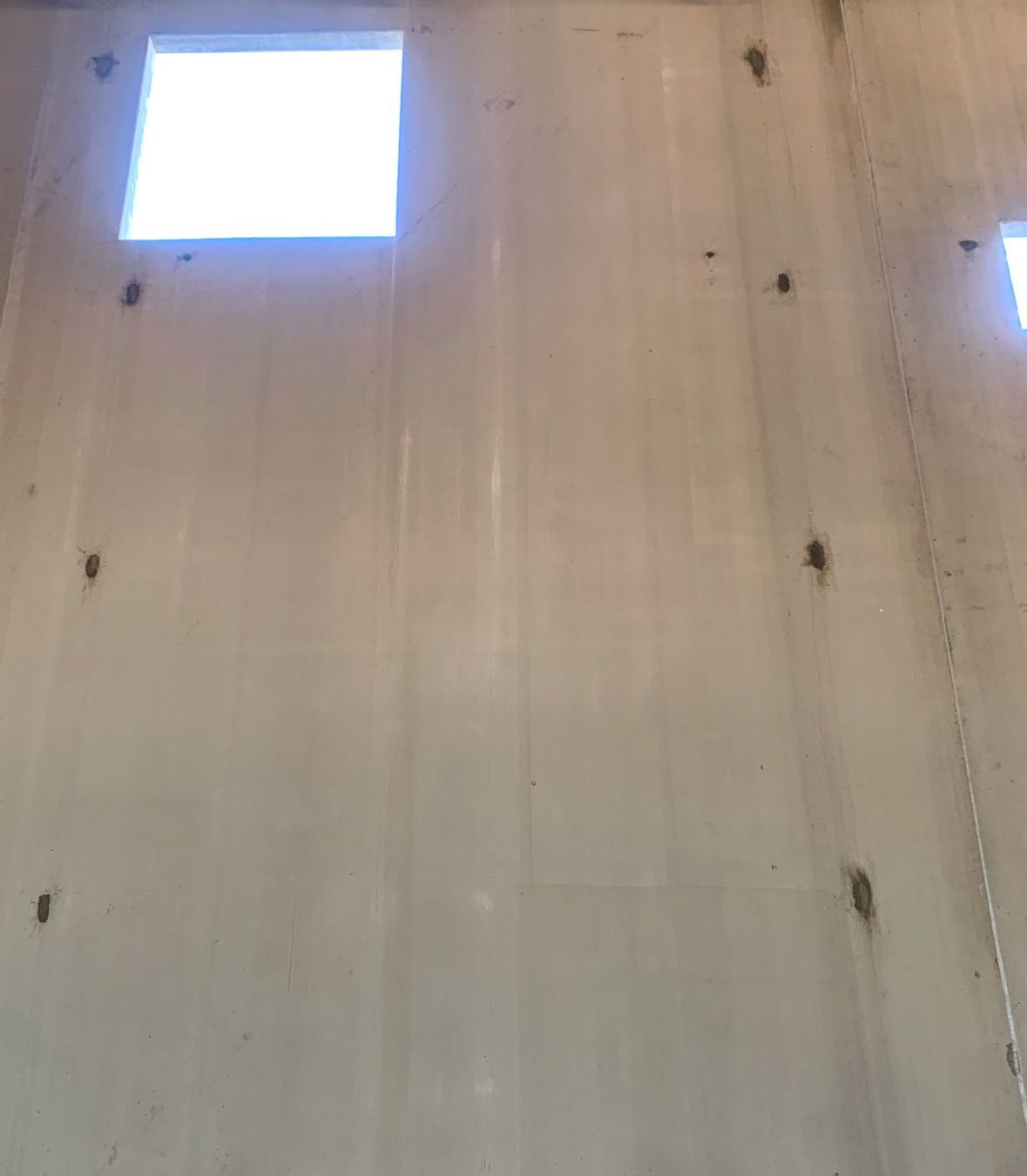 A white wall with a window in the middle of it.