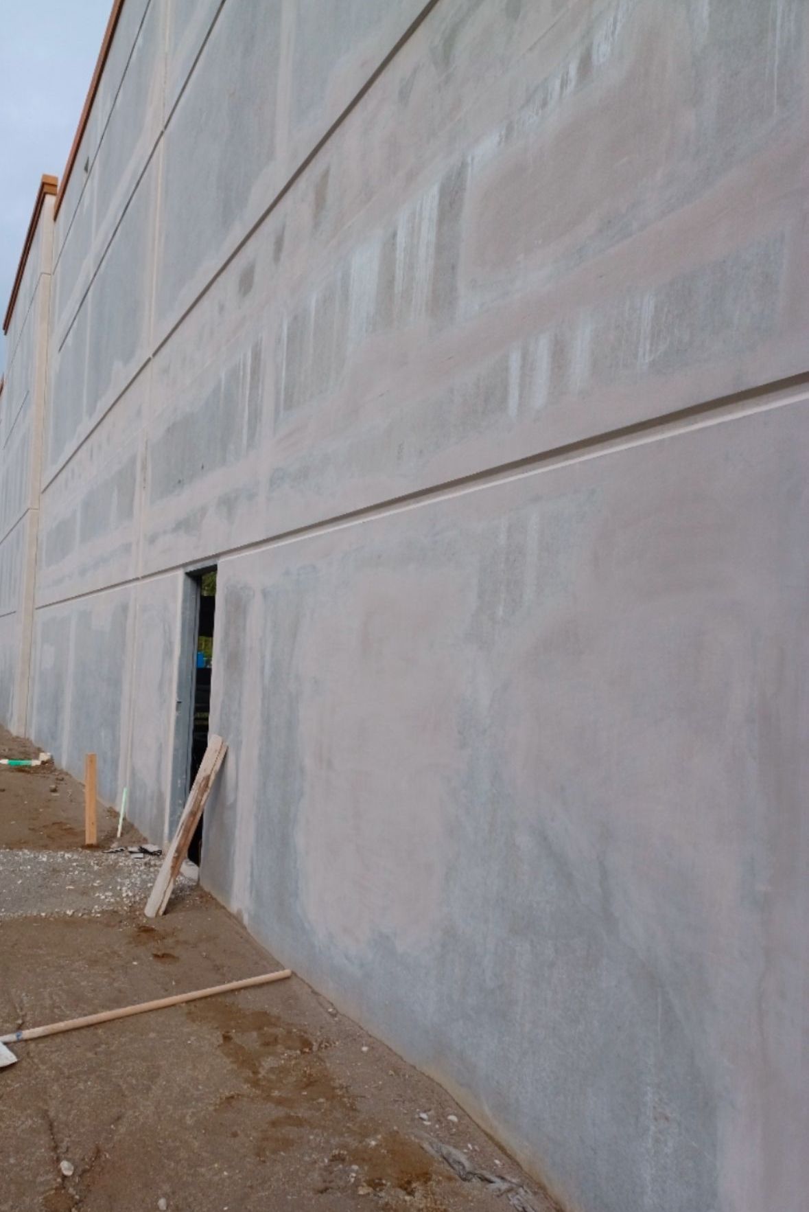 A large concrete wall with a door in the middle of it