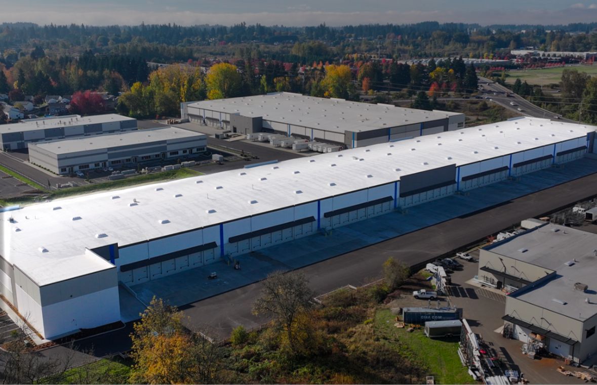 An aerial view of a large warehouse with a white roof.