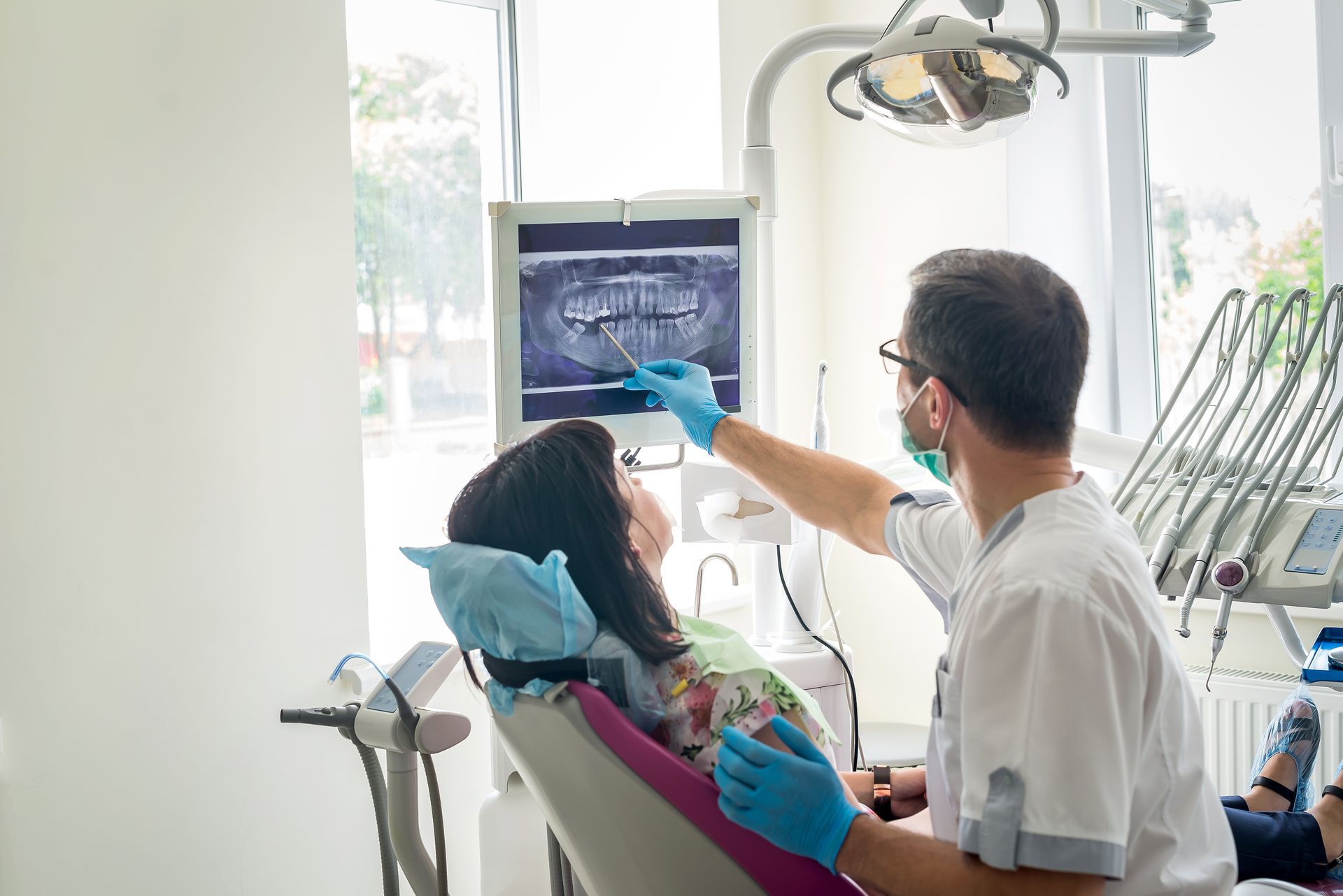 A dentist is showing the patient's teeth on an X-ray at a dental clinic. A dentist is showing the patient's teeth on an X-ray at a dental clinic.