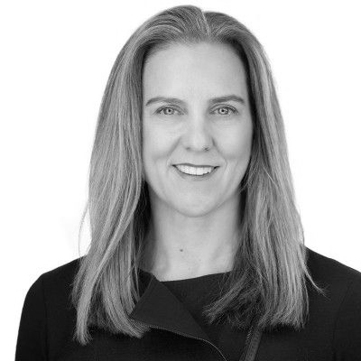 A man in a suit and glasses is smiling in a black and white photo.