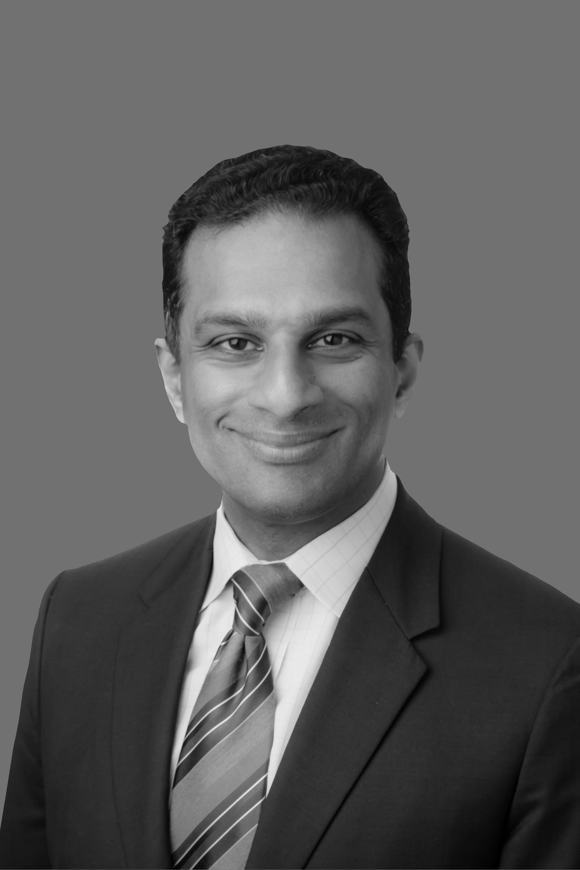 A man in a suit and tie is smiling in a black and white photo.