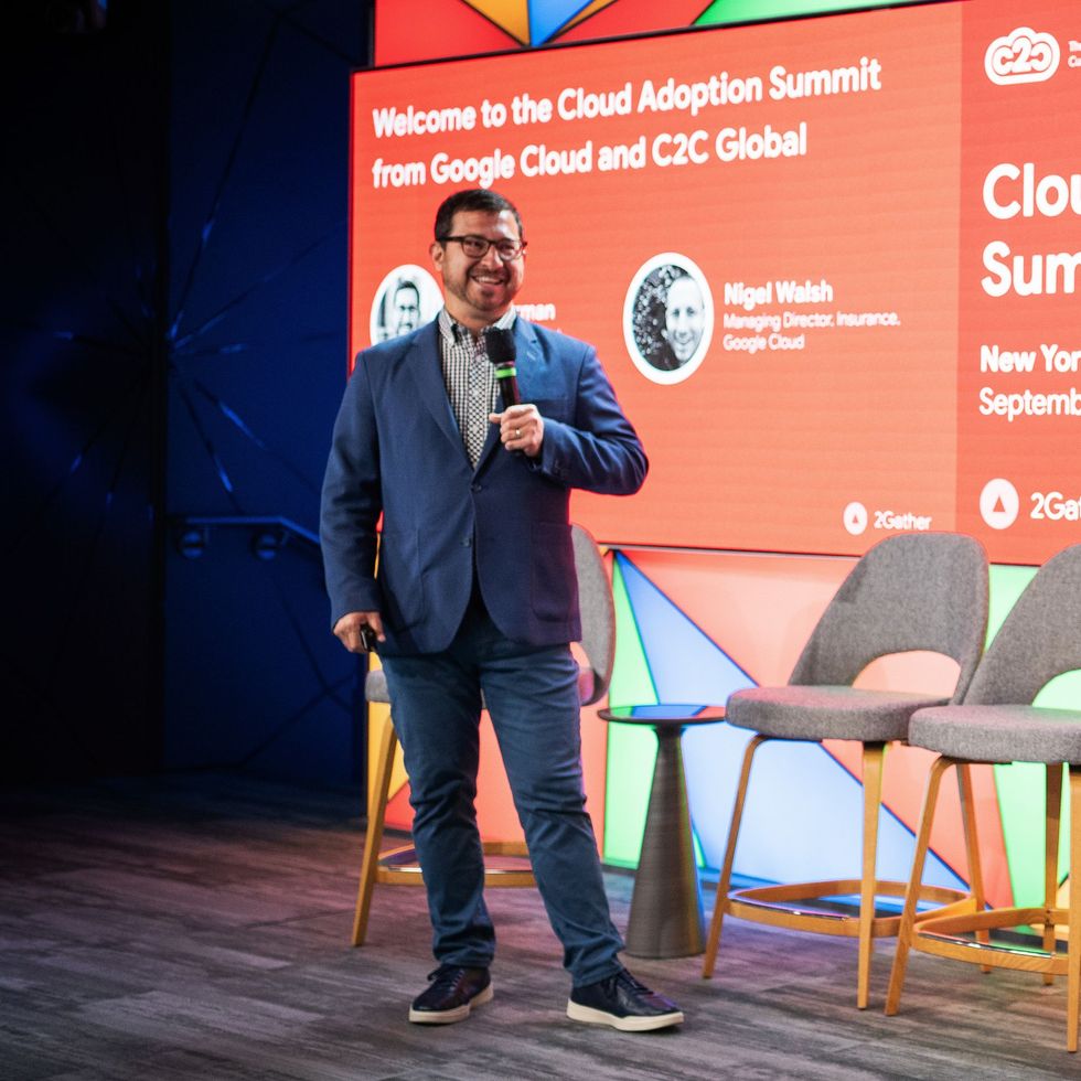 A man stands in front of a large screen that says welcome to the cloud adoption summit