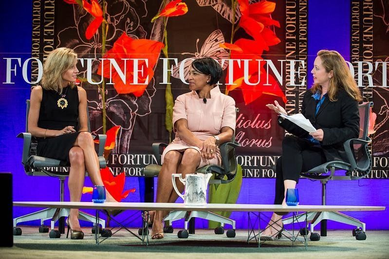 Three women are sitting on a stage in front of a sign that says fortune