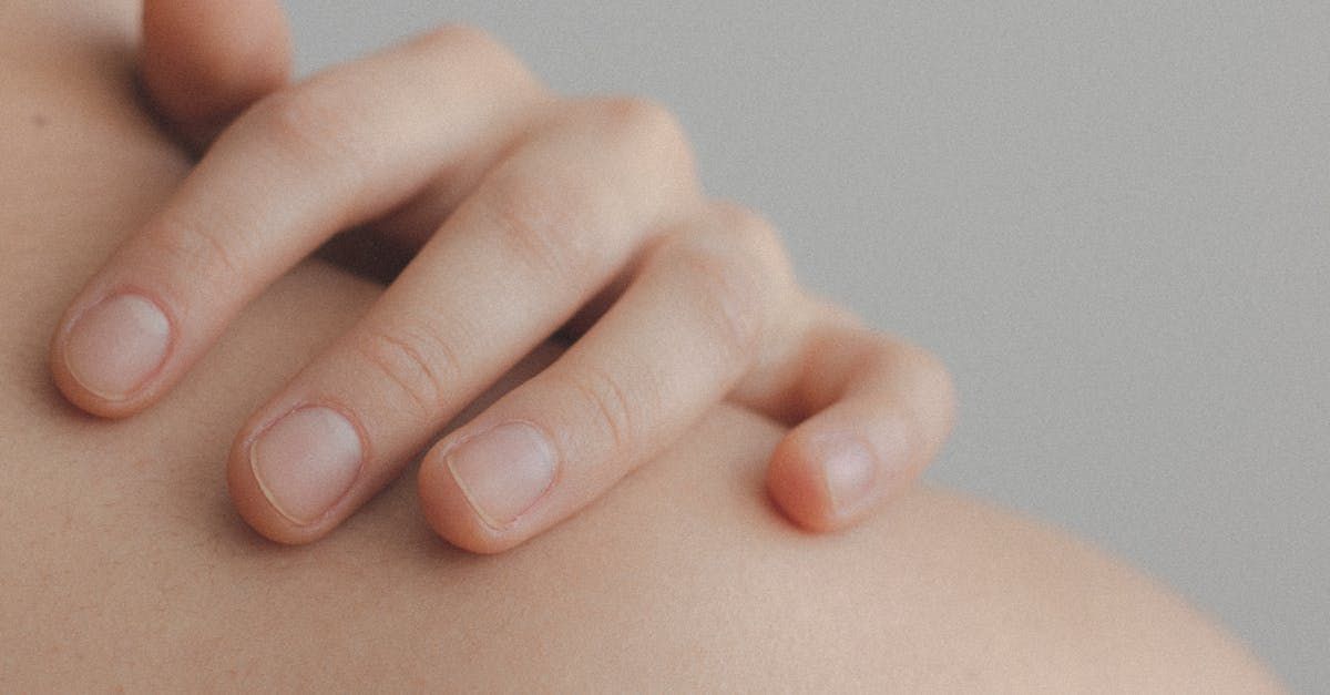 A close up of a person 's hands on their shoulder.