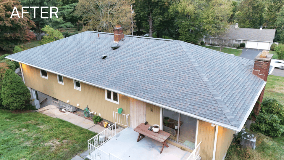 Aerial view of a house with a new gray roof, yellow siding, and a wooden deck.