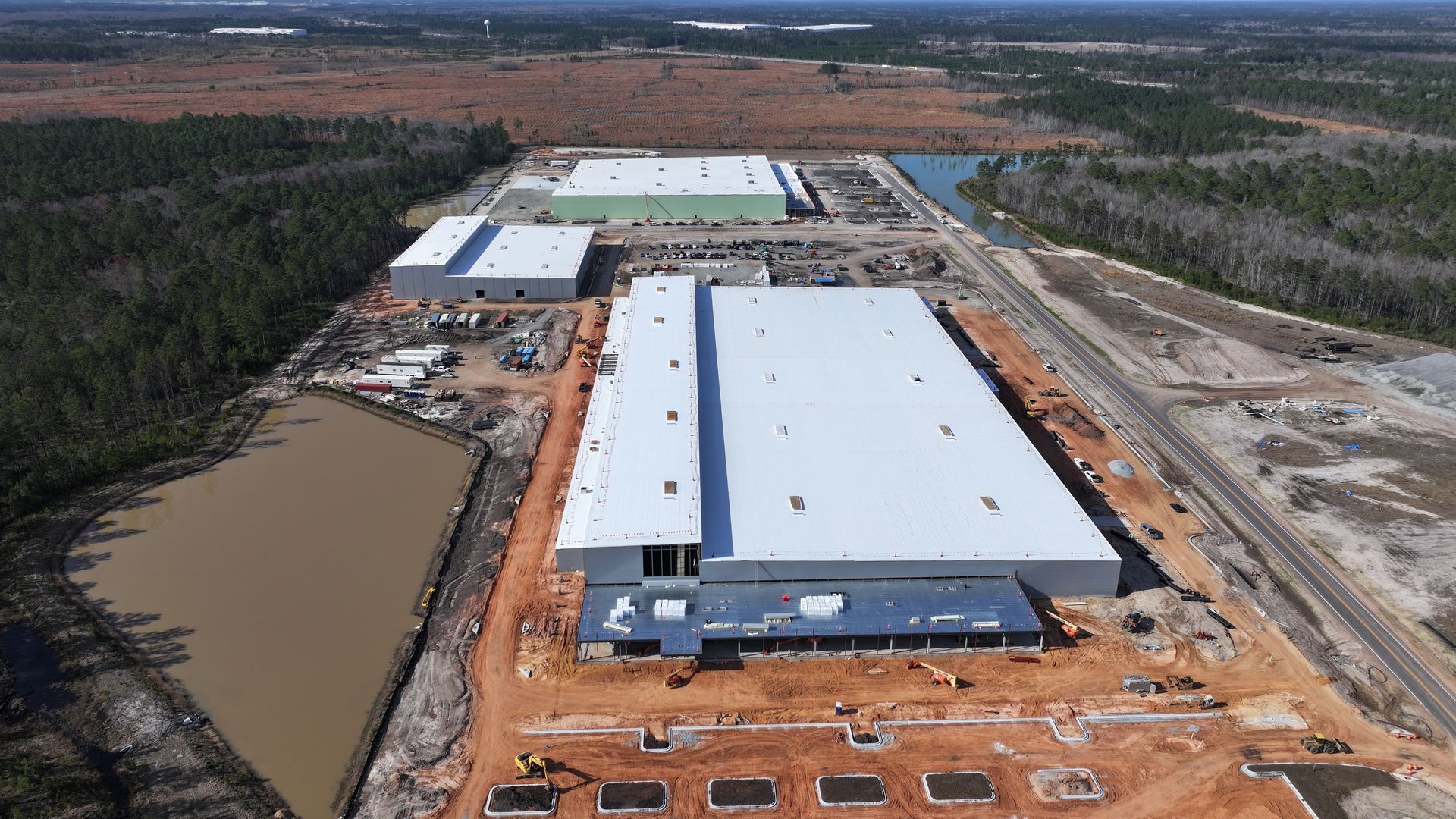 An aerial view of a large building under construction in the middle of a field.