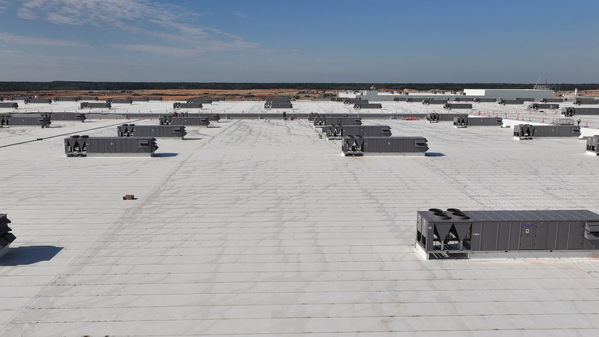 An aerial view of a large white roof with a blue sky in the background.